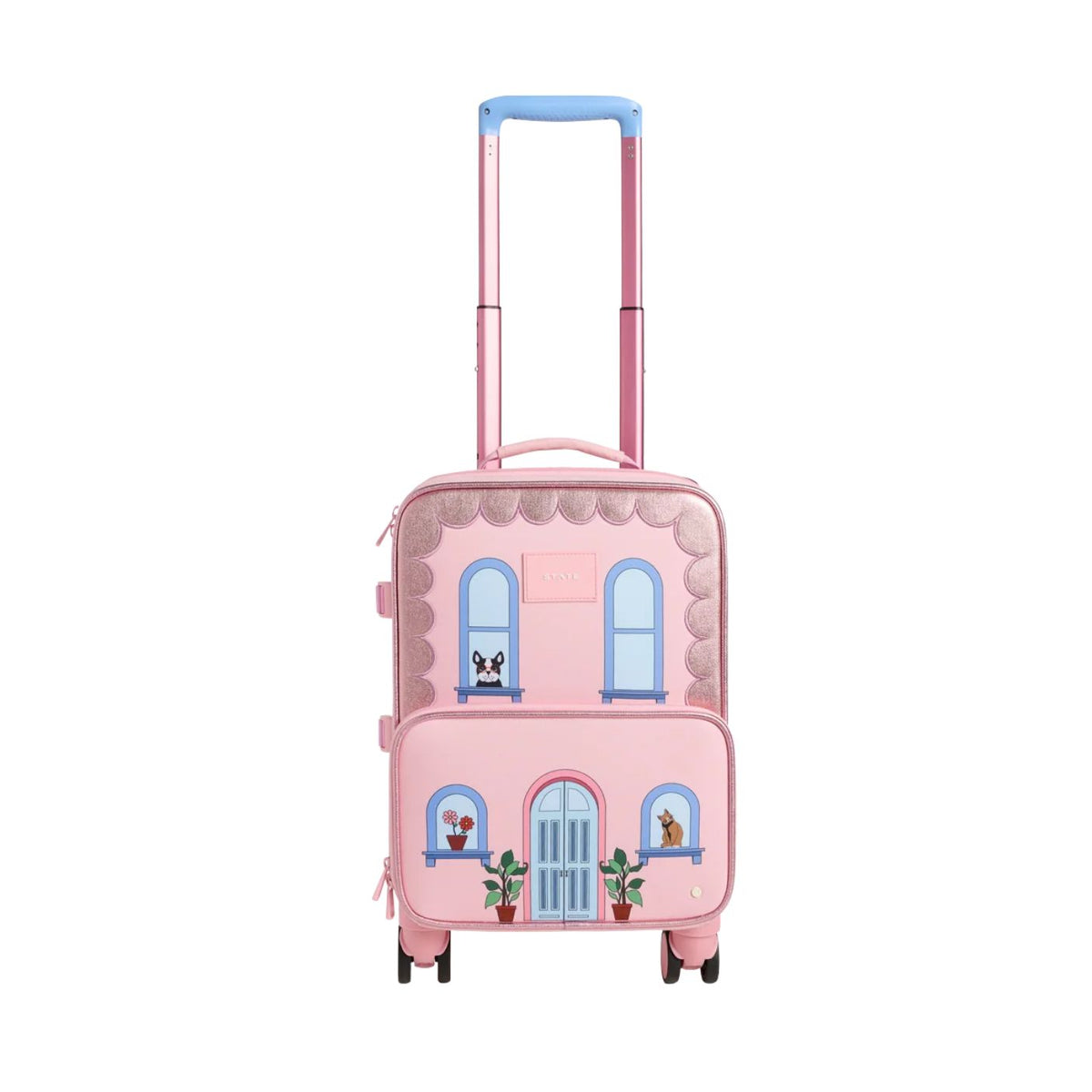 A pink State Bags Mini Logan carry-on suitcase designed to look like a house, featuring a blue telescopic handle, 360-degree spinner wheels, and front graphic details including arched windows, potted plants, and a central blue front door.