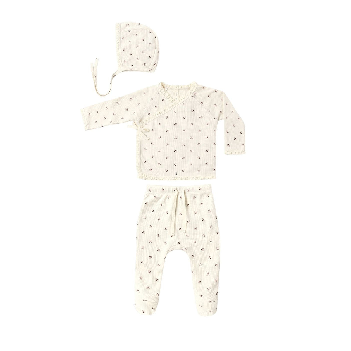 A baby clothing set laid flat on a white background, including a long-sleeve wrap-style top, matching pants, and a bonnet. The set is cream-colored with a small repeating floral print in muted pink and green.