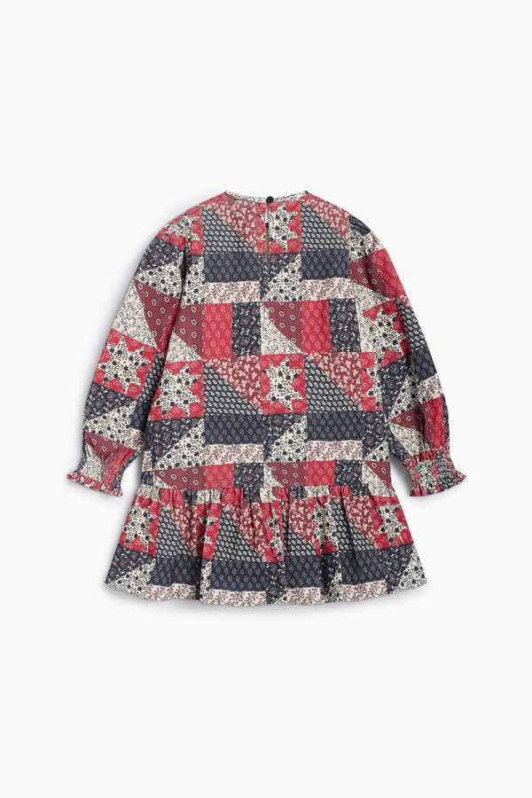 The Quill Dress by The New Society shown laid flat against a white background, featuring a vintage-inspired patch-style print in deep red and blue tones, long sleeves, and a ruffled hem.