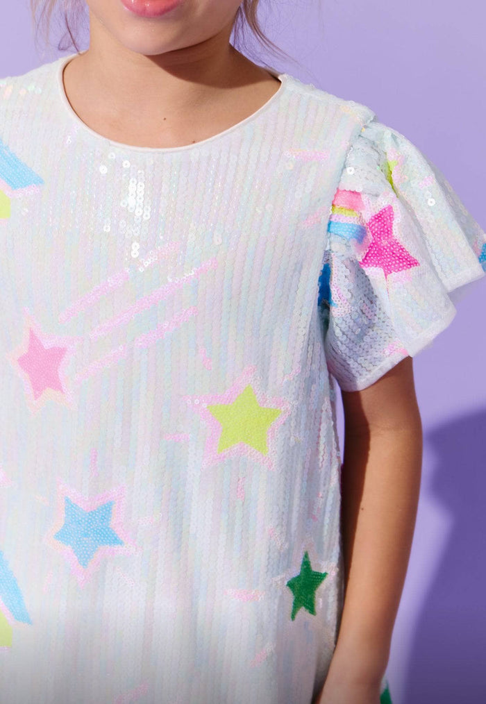 Child wearing a white dress with colorful star patterns against a purple background