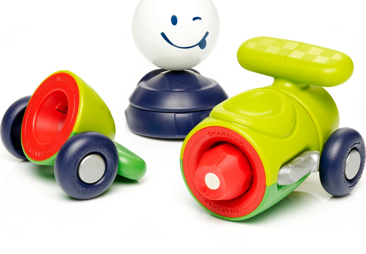 SmartMax My First Car magnetic vehicle set pieces including a green car body with red wheels, a separate red-and-green chassis with wheels, and a white smiling character ball figure.