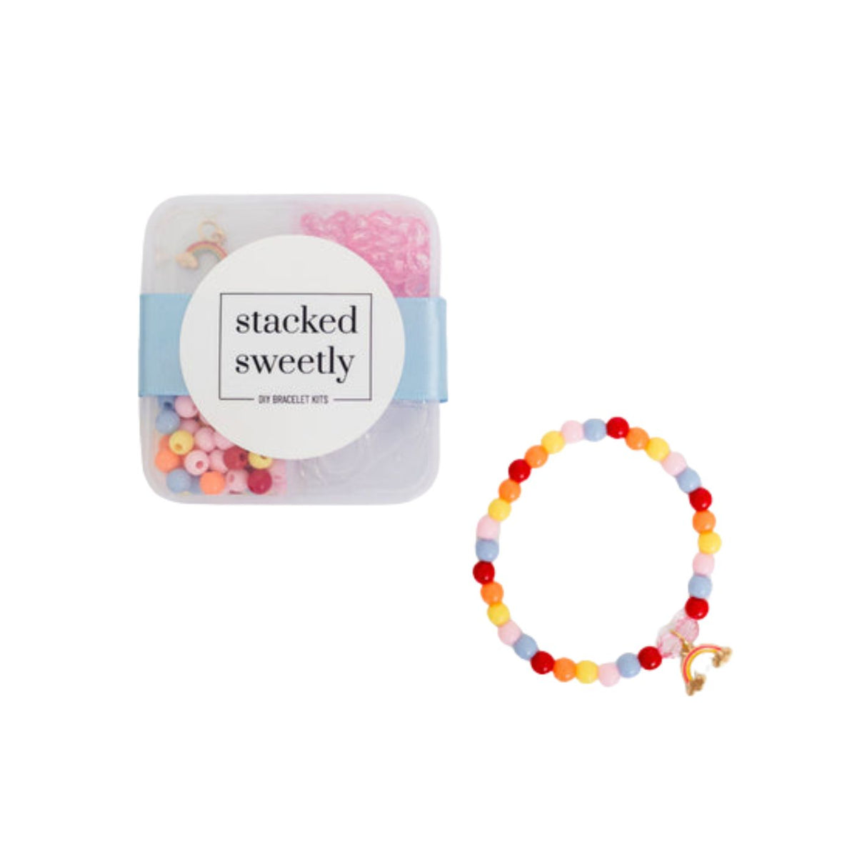 A clear plastic storage box labeled "stacked sweetly" containing pink and colorful beads, displayed alongside a finished stretchy bracelet featuring pastel and primary-colored beads with a gold rainbow charm against a white background.