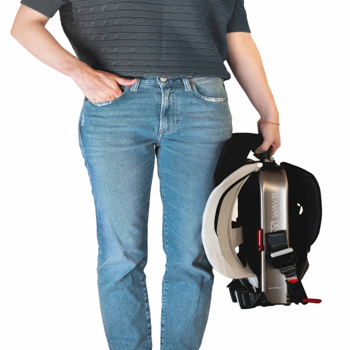 Person wearing blue jeans holding a black and white backpack with visible branding.