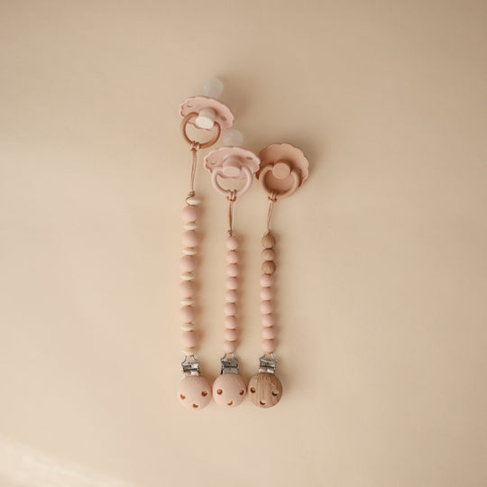 Pink baby teething ring with beads on a beige background