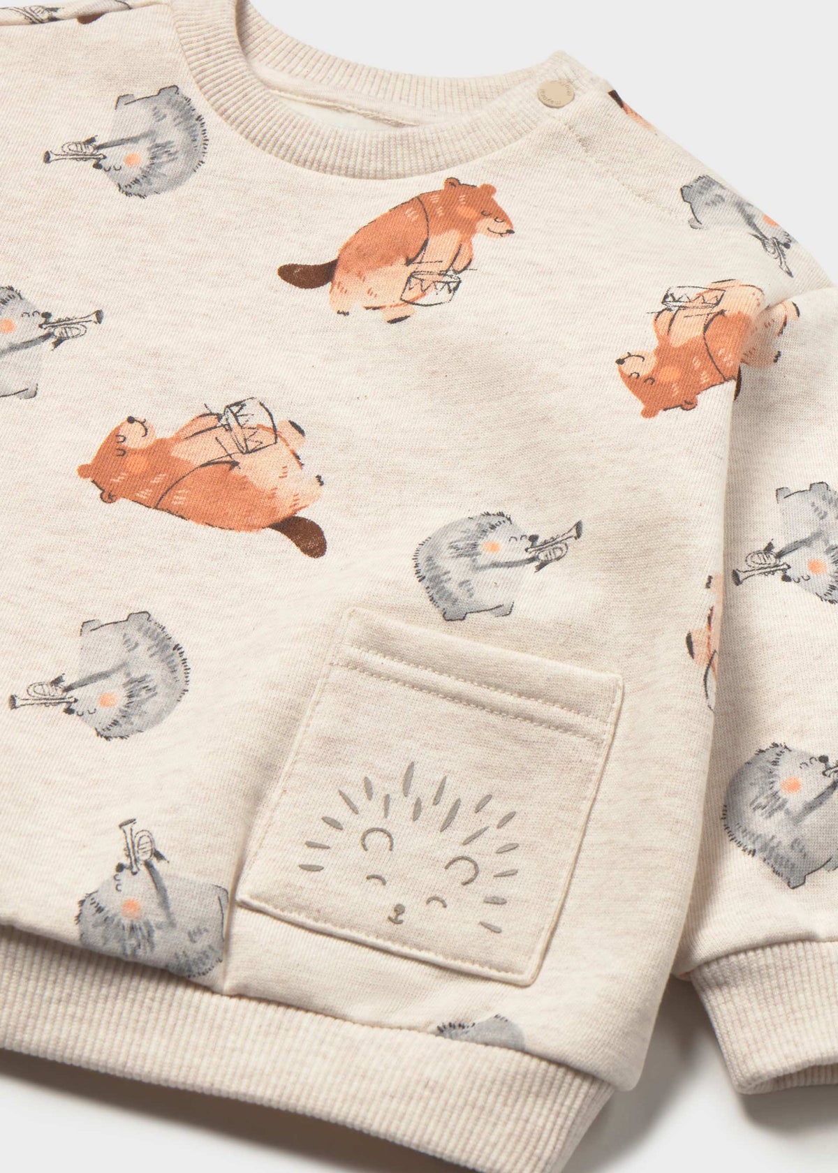 A close-up of a children's cream sweatshirt featuring an all-over print of orange hedgehogs and gray rabbits, with a front pocket decorated with a stitched hedgehog face.