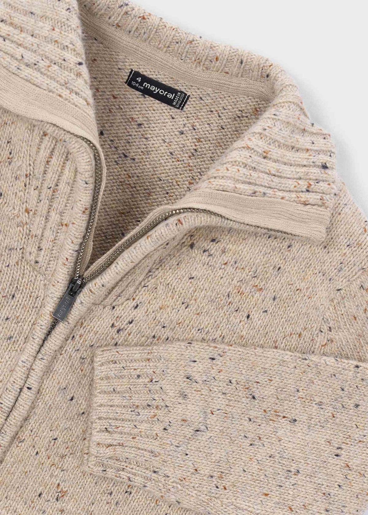 Close-up of a beige textured sweater with a zipper, featuring a brand label.