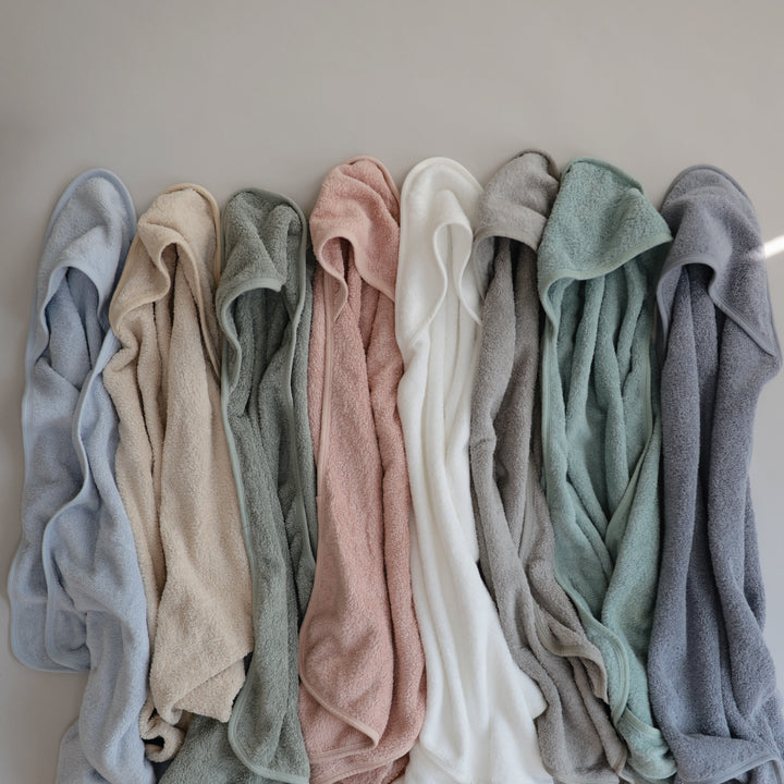 Row of folded towels in various colors against a neutral background