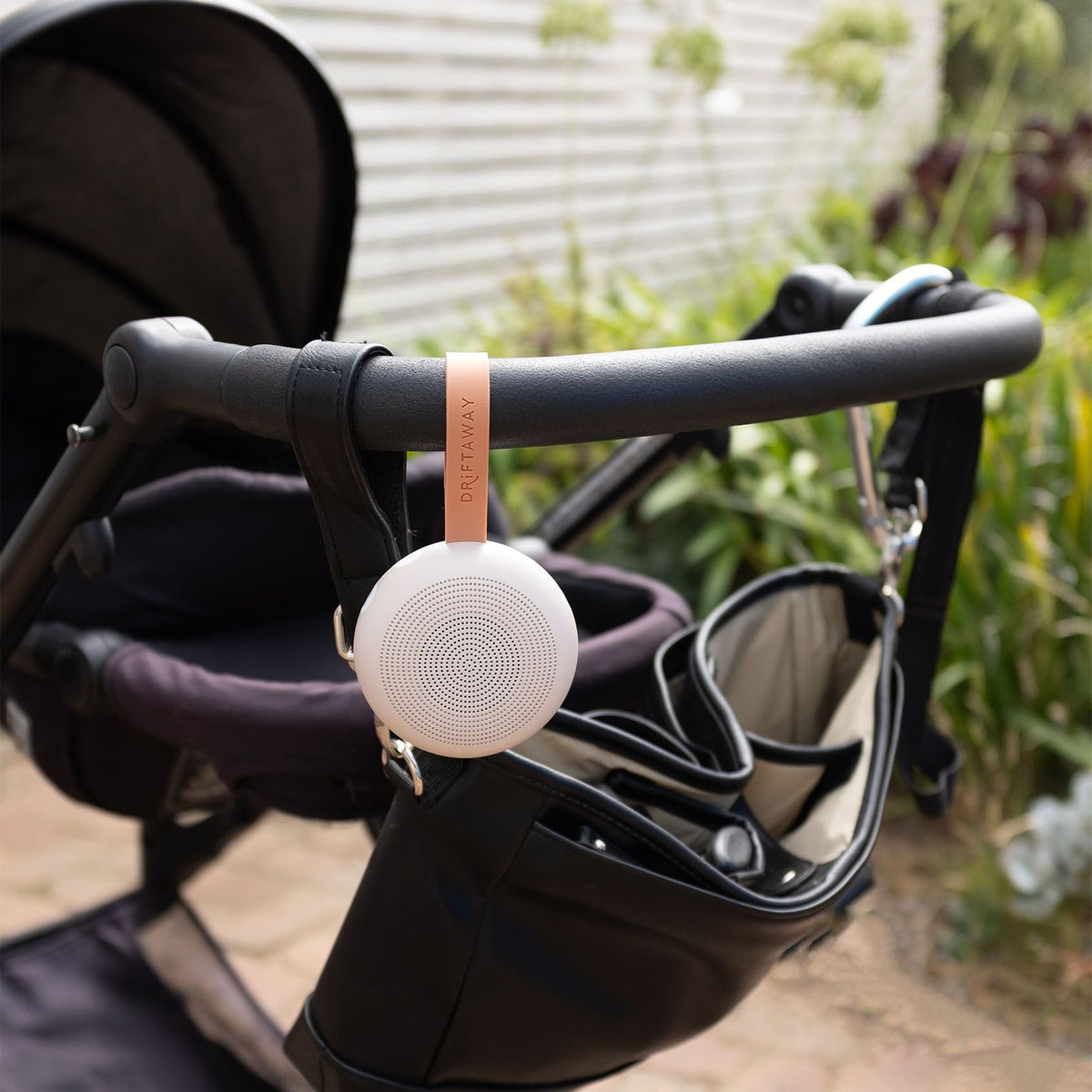 White round device attached to a stroller with a garden background