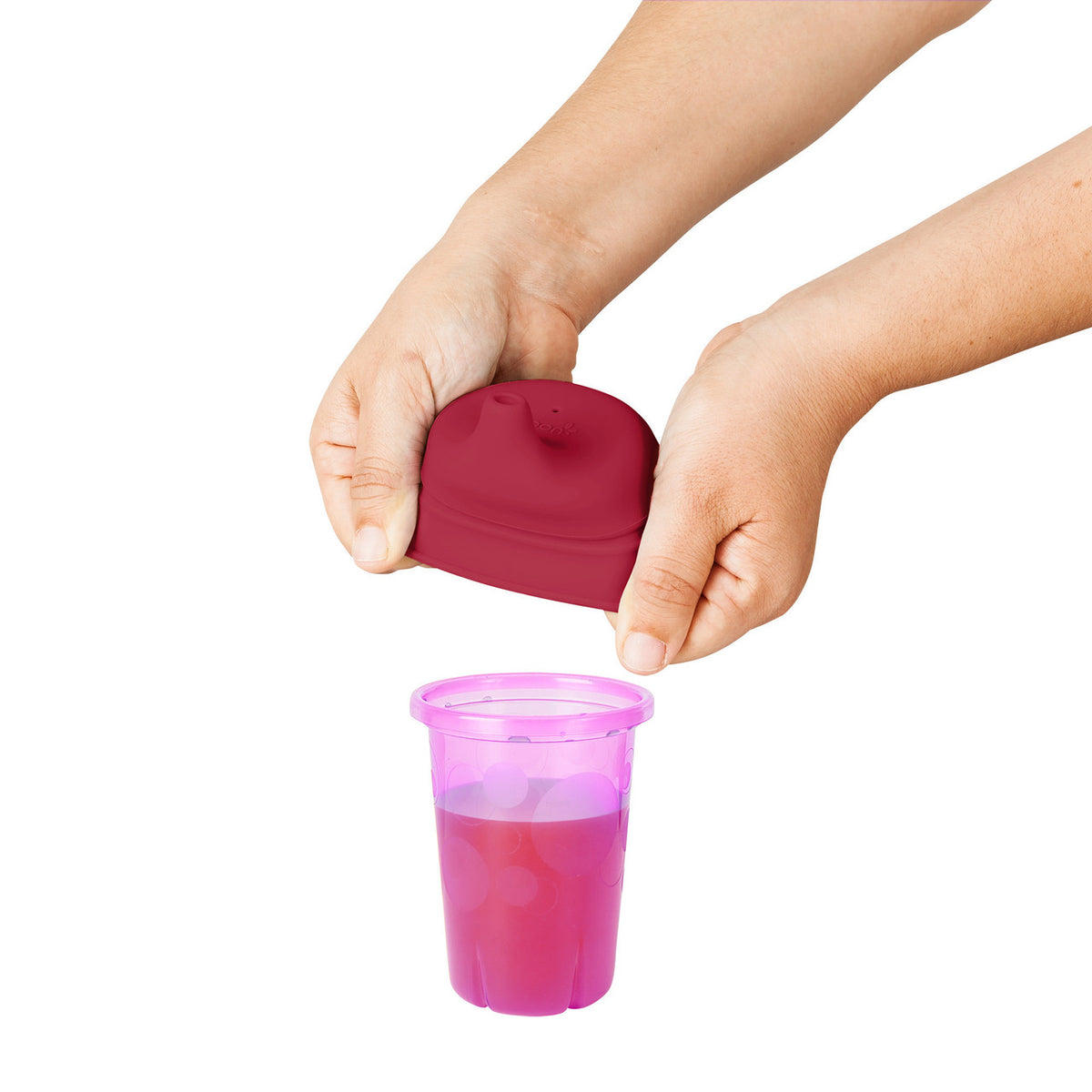 Child's hands opening a pink lid on a purple cup against a white background