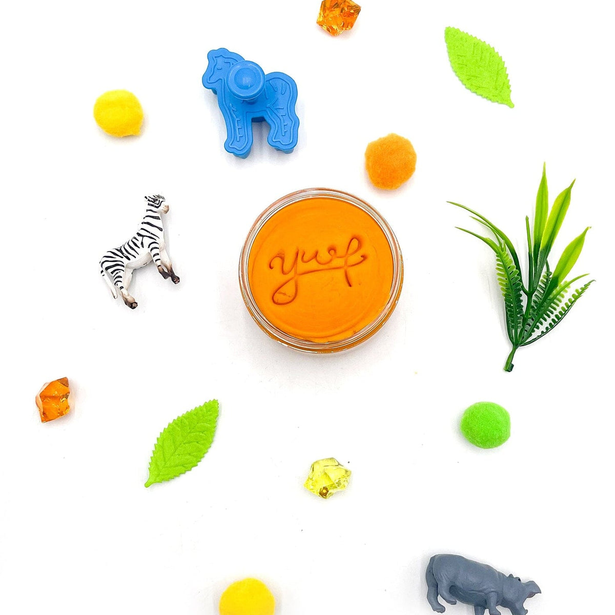 Small container of 'yup' jelly with animal figurines and leaves on a white background