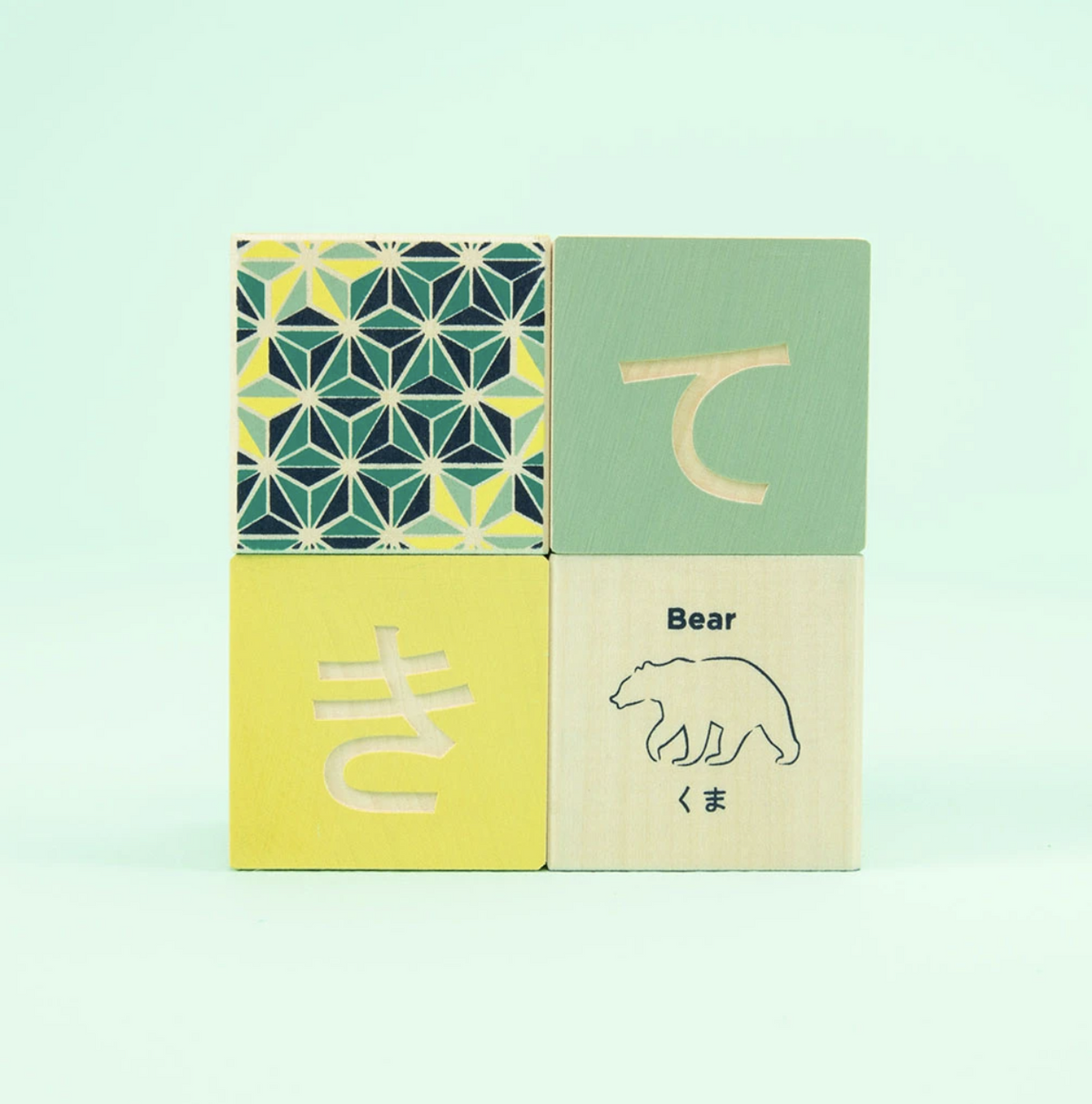 4 stacked olorful wooden blocks with Japanese text and patterns on a mint background