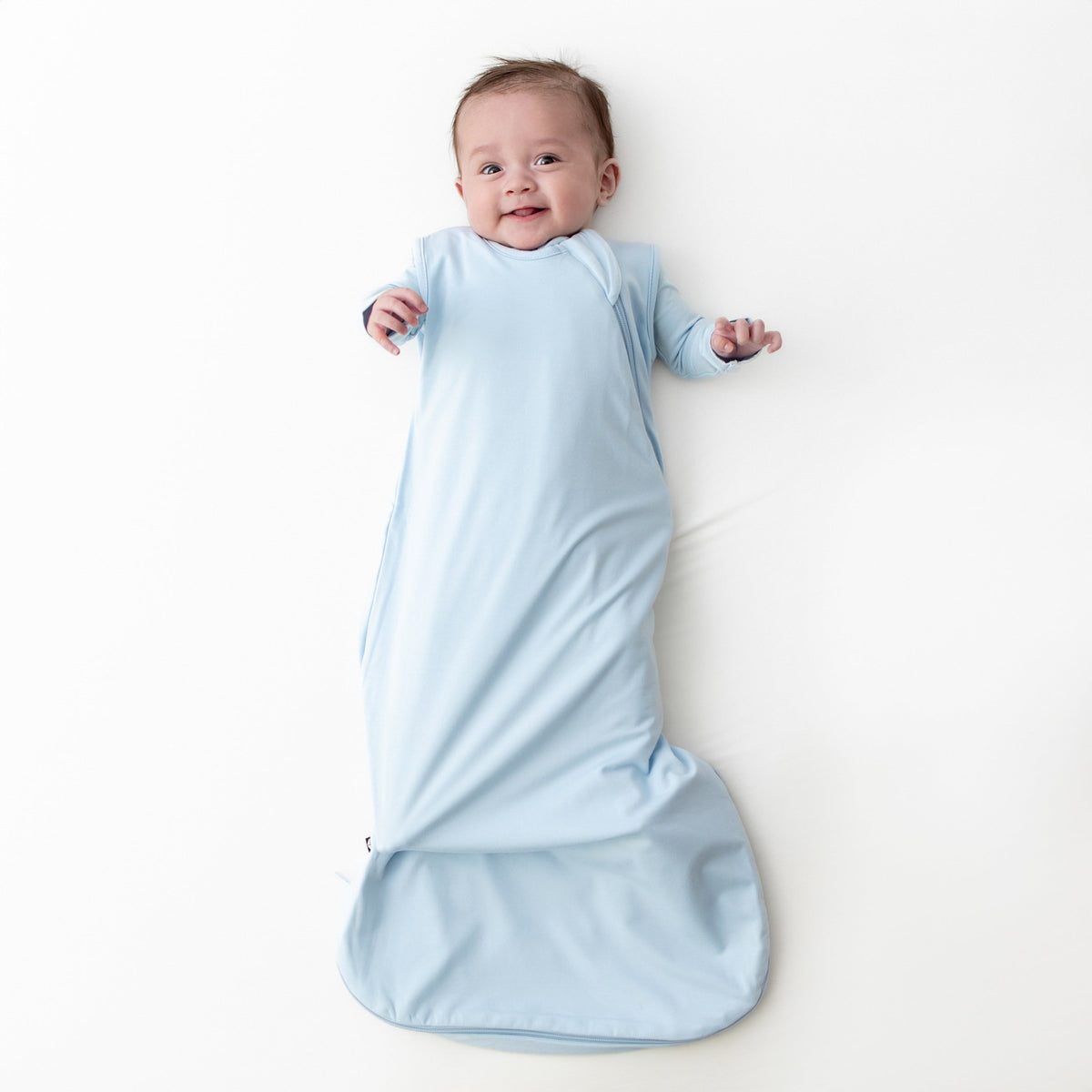 Baby wrapped in a light blue swaddle on a white background