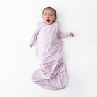 Baby wrapped in a purple swaddle on a white background