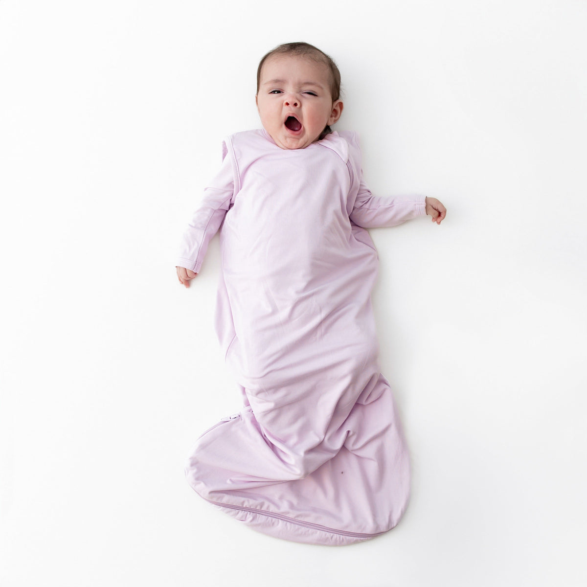 Baby wrapped in a purple swaddle on a white background