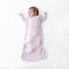 Baby in a pink sleep bag lying on a white background