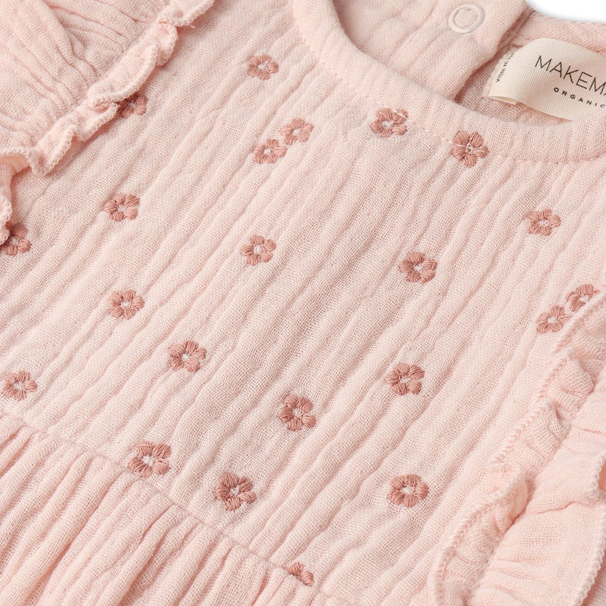 Close-up of a pink textured fabric with floral patterns and a visible brand label.