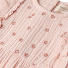 Close-up of a pink textured fabric with floral patterns and a visible brand label.