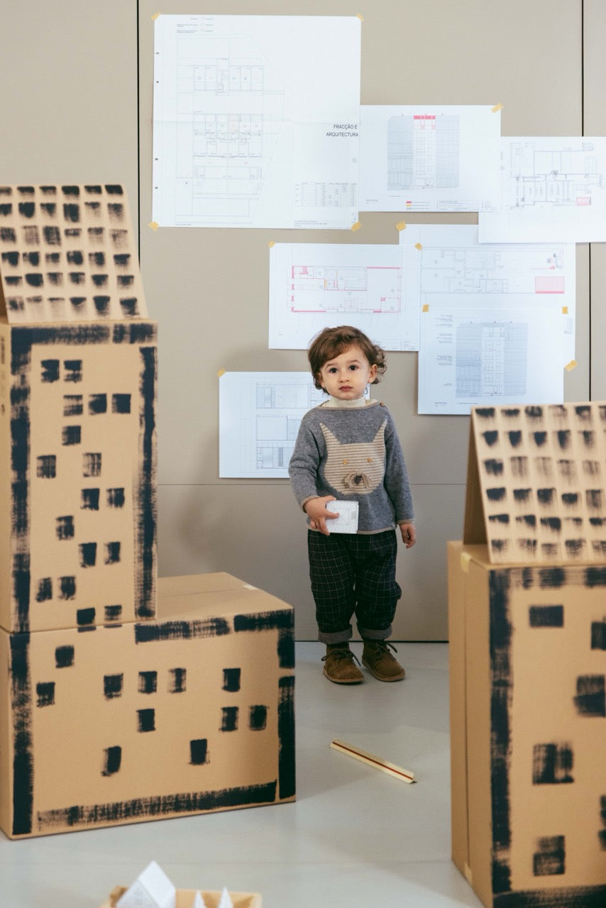 Child playing with cardboard cityscape models indoors