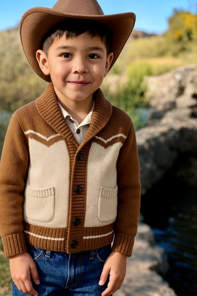 Child wearing a brown and beige cardigan with a cowboy hat outdoors.