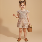 Young girl in a floral dress holding a basket with flowers on a beige background