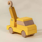 Yellow toy truck with wooden elements on a beige background
