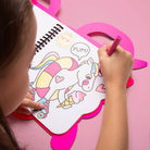 Child coloring a unicorn with pink crayon on a pink surface