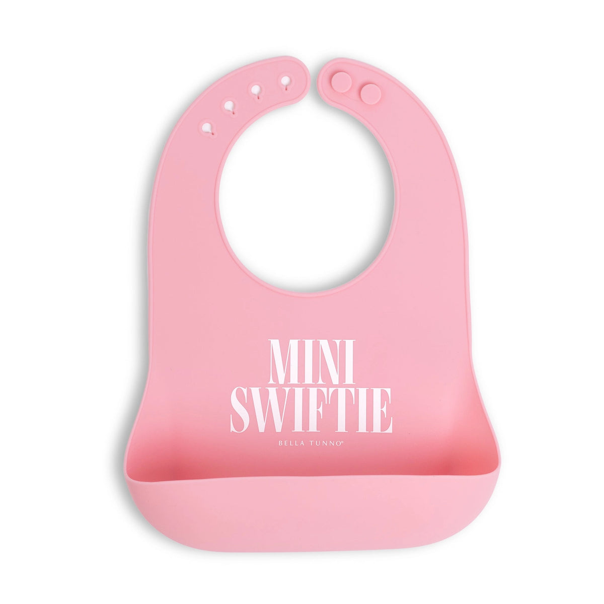 A pink silicone baby bib with a wide chin guard and front pocket, featuring the text 'MINI SWIFTIE' and 'BELLA TURNUP' printed in white. The bib is shown on a clean white background with a soft drop shadow.