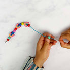 Colorful bead bracelet being adjusted on a white background
