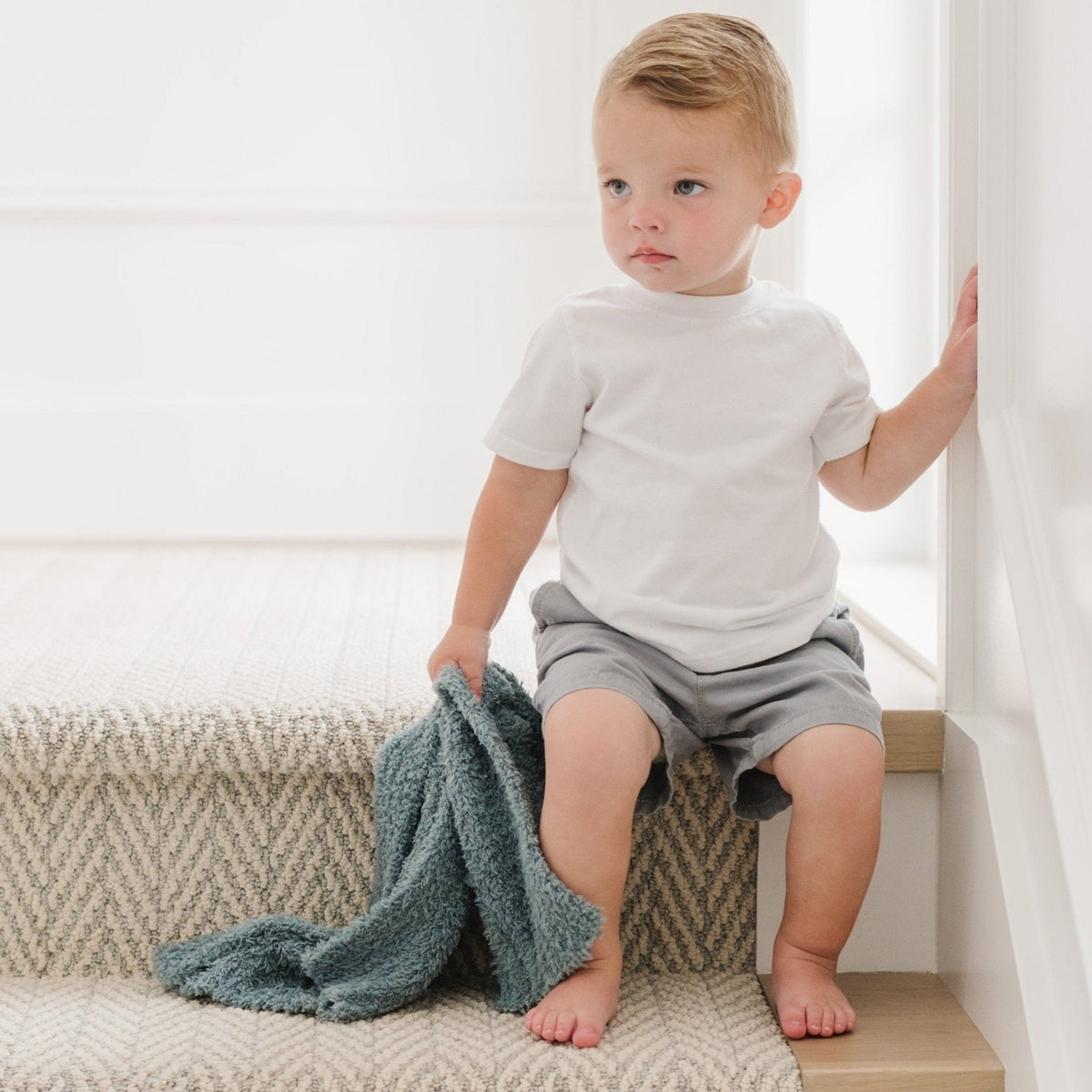 Child sitting on a step with a blue blanket