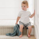 Child sitting on a step with a blue blanket