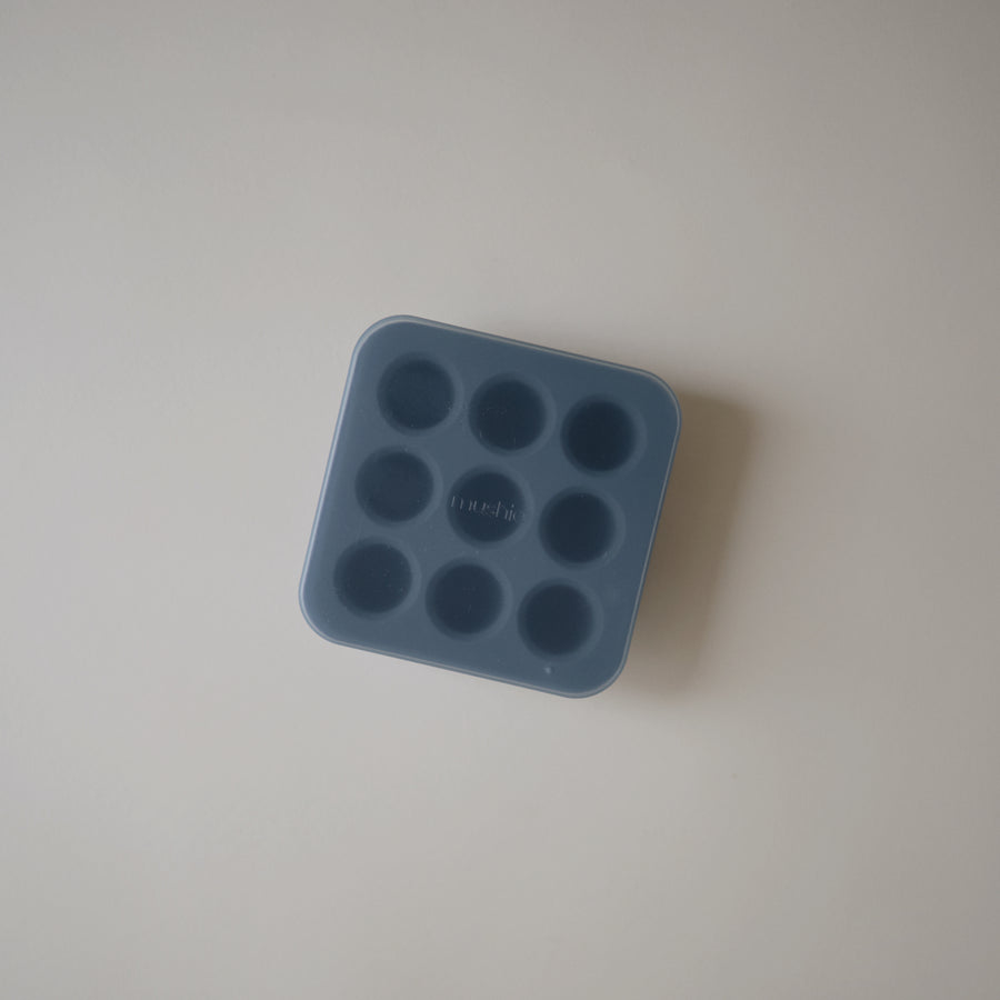Blue silicone mold with multiple round cavities on a light gray background