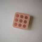 Pink silicone mold with multiple round cavities on a light gray background