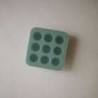 Green silicone ice cube tray on a light gray background