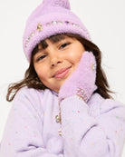 A young girl wearing a fuzzy lavender knit beanie and matching knit mittens with jeweled embellishments, posed against a clean white background.