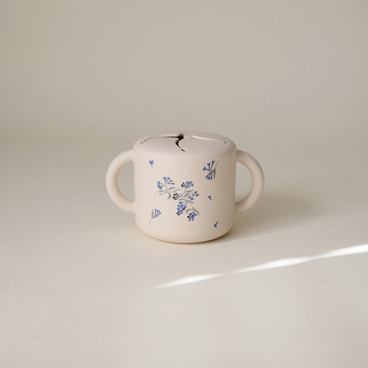 White ceramic mug with blue floral patterns on a light beige background