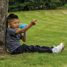 Child sitting on grass pointing towards a tree