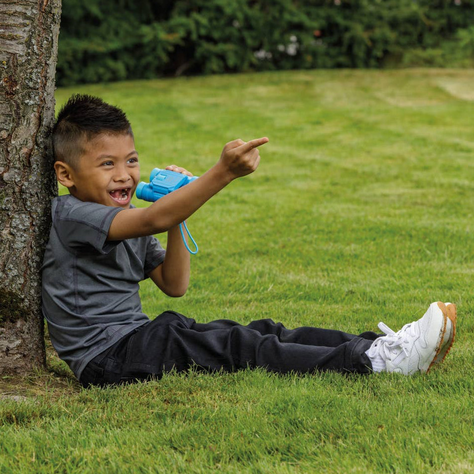 Child sitting on grass pointing towards a tree
