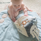 Baby playing with a soft toy on a textured blanket