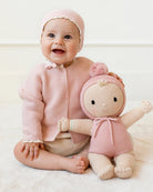 Baby in pink outfit with matching doll on a white background