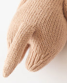 Close-up of a beige knitted mitten on a white background