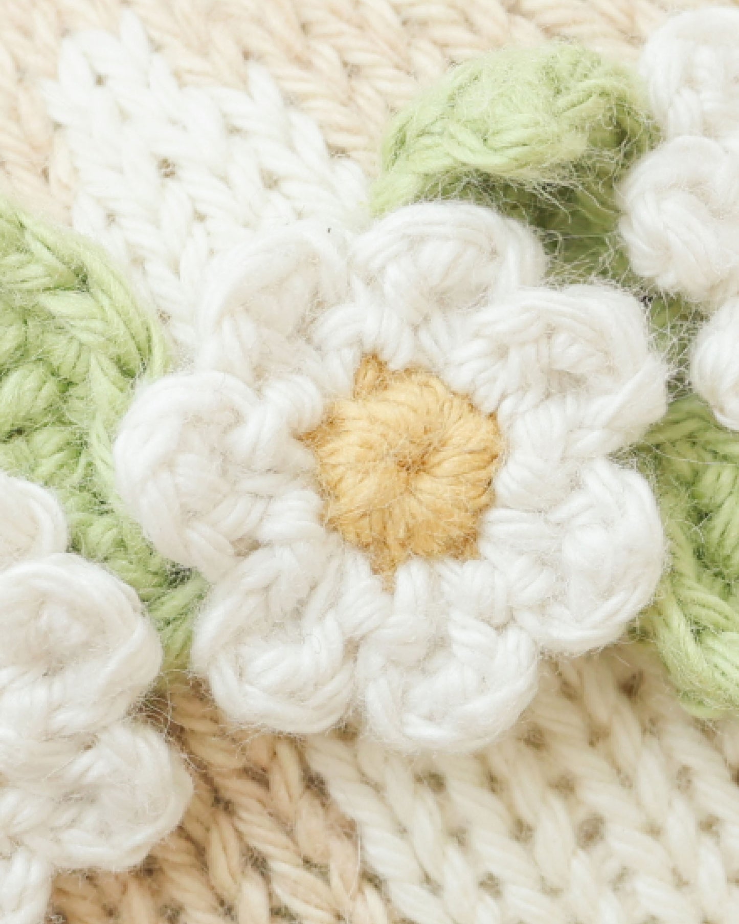 Close-up of a knitted flower with a gold center on a textured fabric background