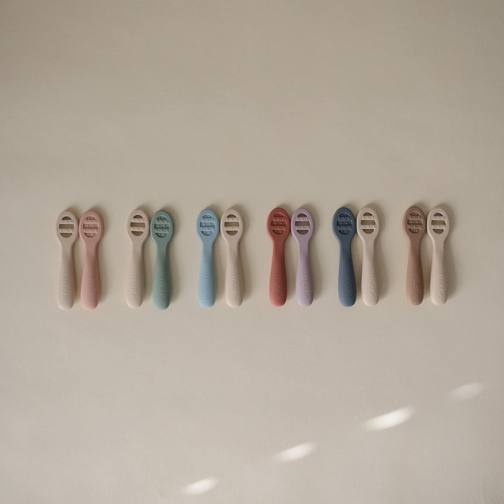 Row of baby teethers in various colors on a light background