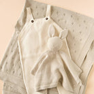 Beige baby romper with bunny ears on a textured beige blanket