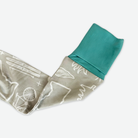 Folded fabric with teal top and beige bottom featuring white graphics on a light gray background