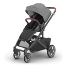 A modern stroller in dark gray and black with brown handle accents, shown at a three-quarter angle on a clean white background.