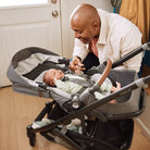 Man interacting with a baby in a stroller indoors