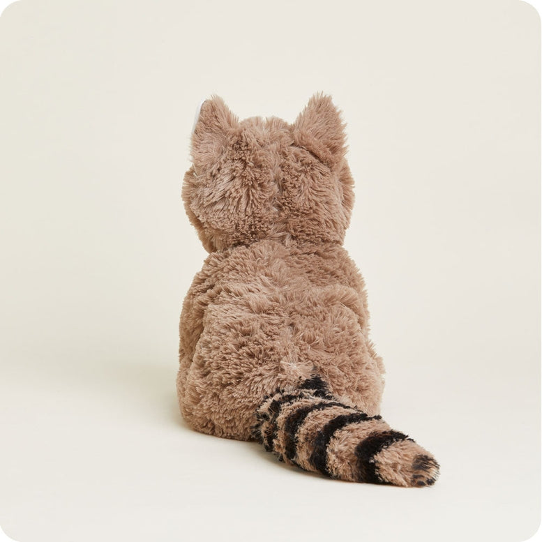 A rear-view studio product photo of a plush Raccoon by Warmies sitting against a light background, highlighting its textured brown fur, pointed ears, and characteristic striped tail.