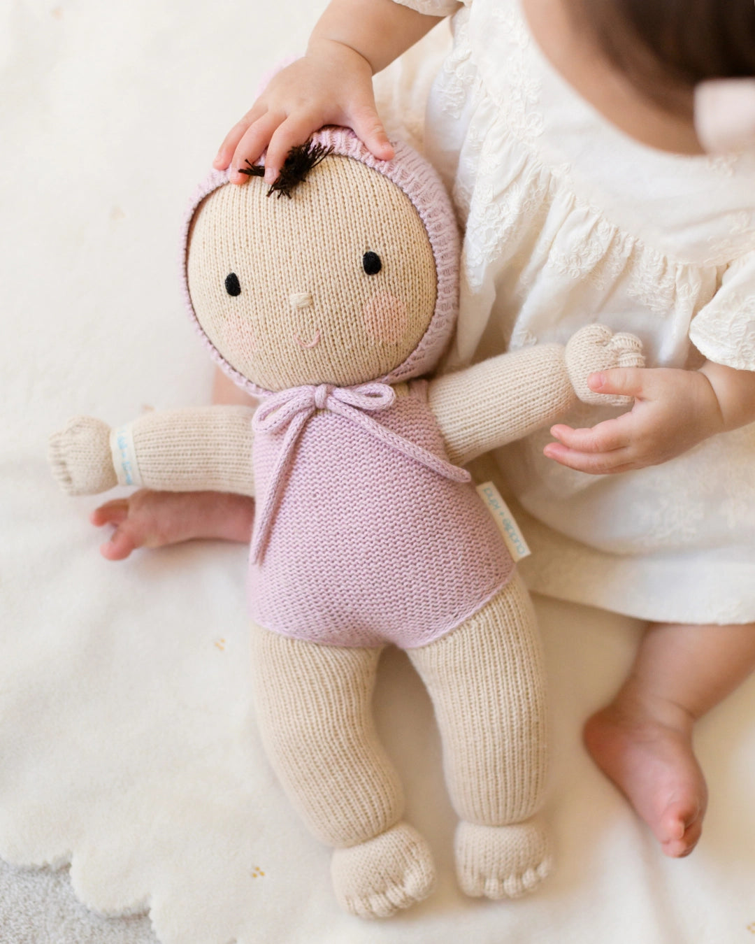 Knitted doll held by a child on a soft surface