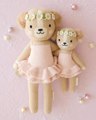 Two teddy bears in ballet costumes with flower crowns on a pink background