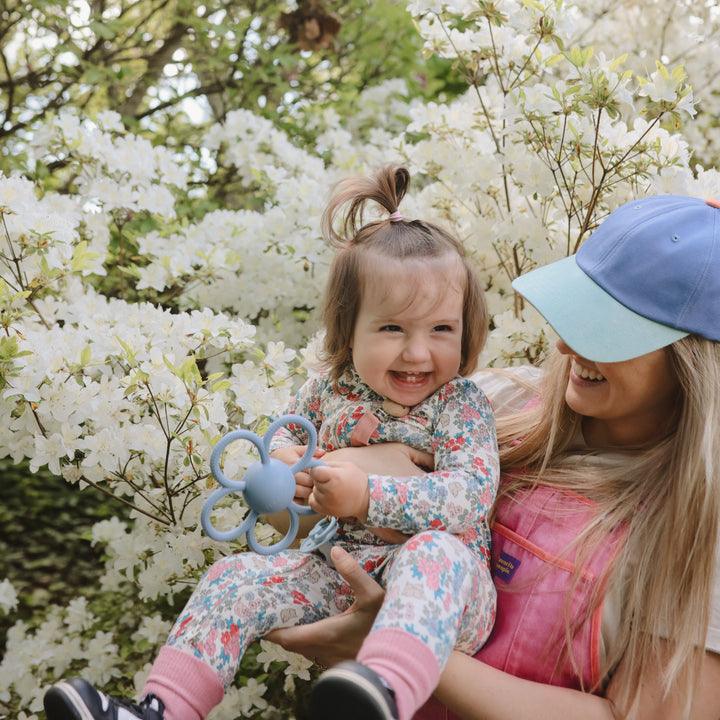 Woman holding a child in front of white blossoms